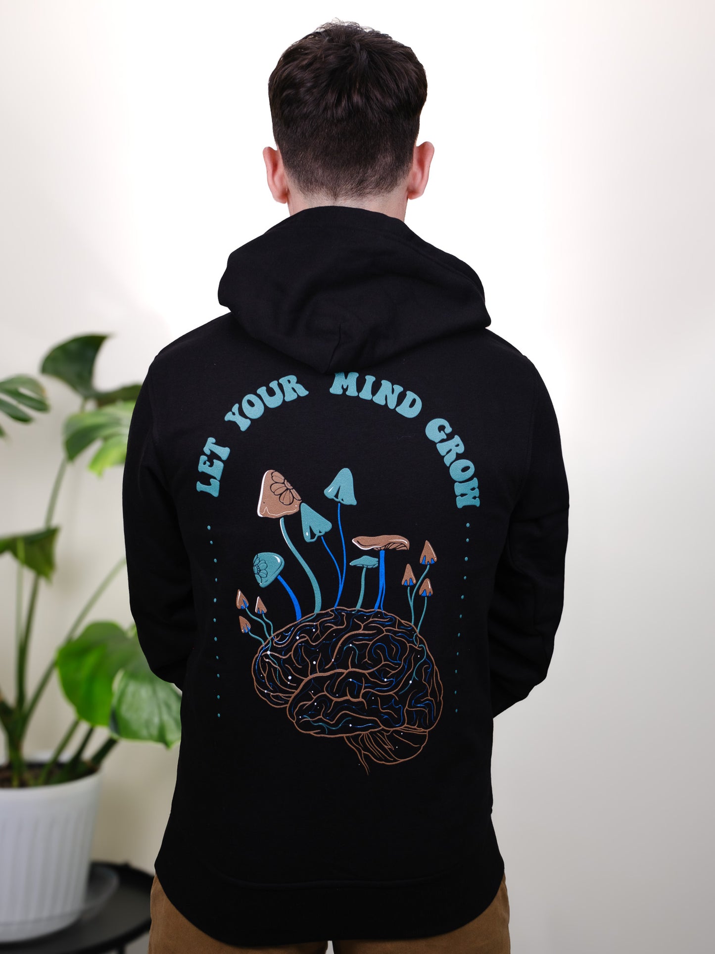 Let Your Mind Grow hoodie back design on a male model, featuring detailed mushroom and floral tattoo-inspired art.