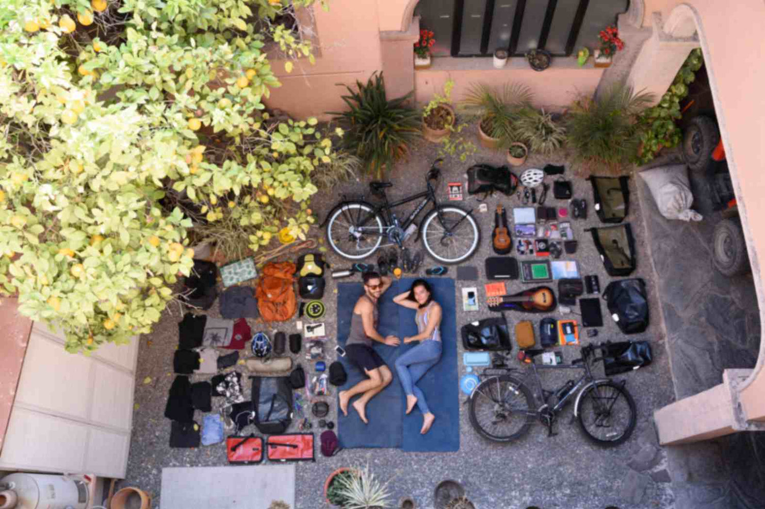 Overhead photo on the Our Artists page showing Kansinee and her partner on yoga mats surrounded by bicycles and gear, illustrating their travel tattoo adventures across Mexico.