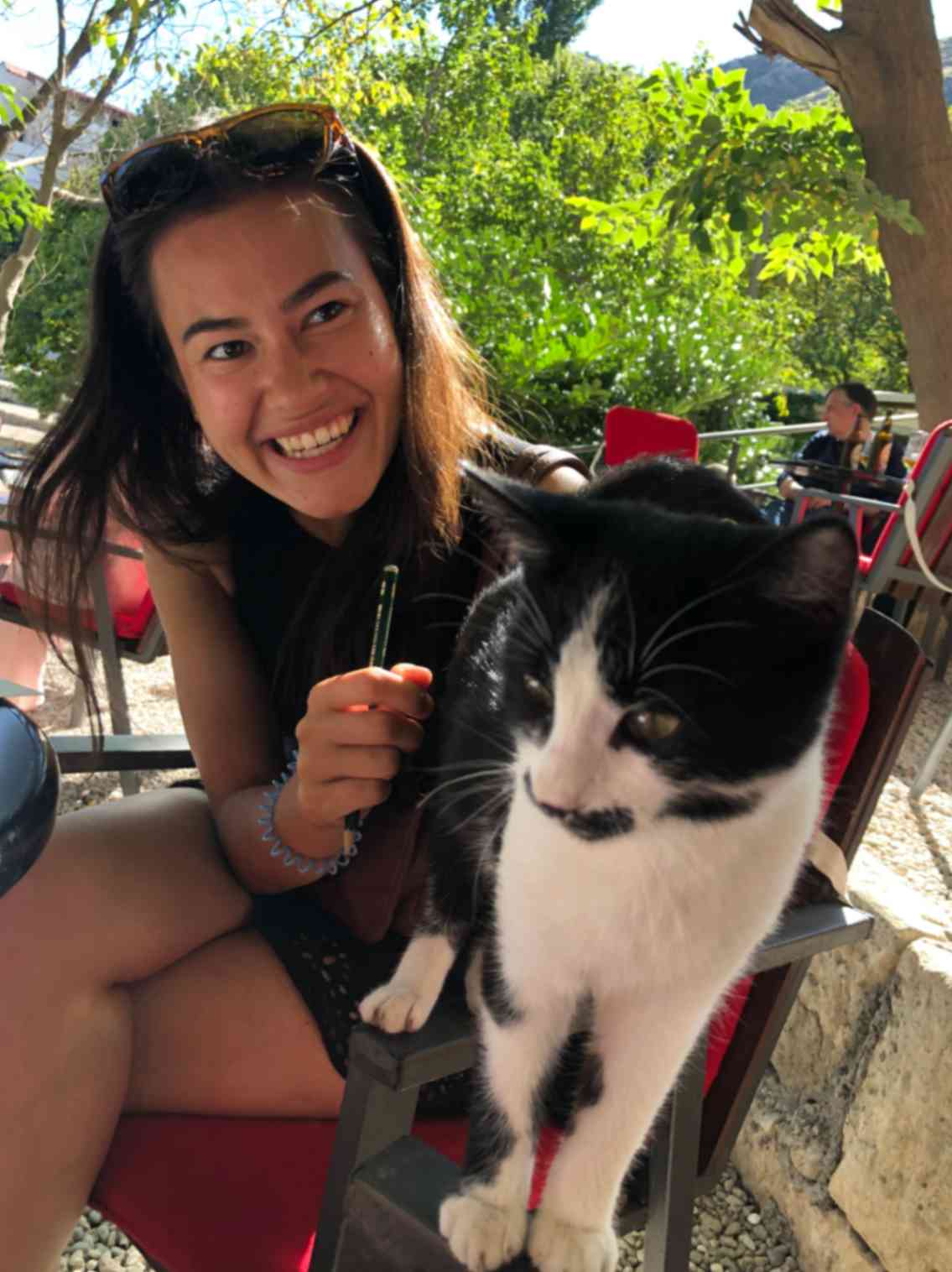Kansinee enjoying a sunny day playing with a cat, captured on the Our Artists page. This image relates to her role in promoting positive mental health through art.