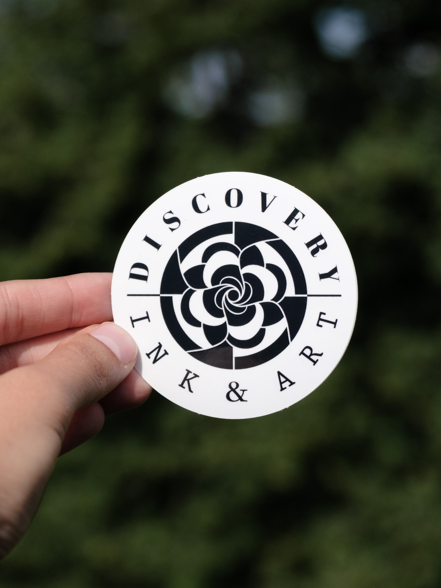 The Discovery Ink & Art Logo featuring: Discovery Ink & Art circled around a mandala-inspired floral logo