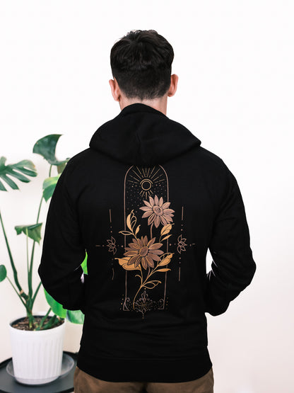 Male model wearing Follow the Sun hoodie, back view featuring vibrant sunflower design with fine line detailing