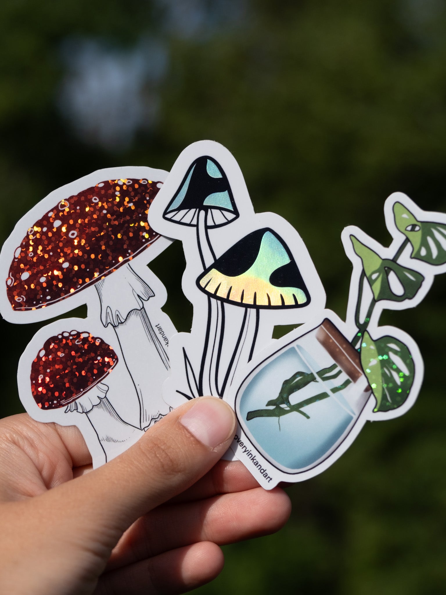 Three stickers: Amanita mushroom, holographic black mushrooms, and a monstera plant in a propagation jar.