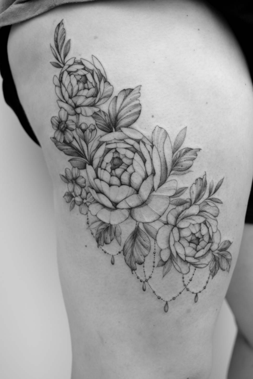 Floral and geometric fine line tattoo on a person's quad, showcasing intricate artistry and design on the FAQ page.