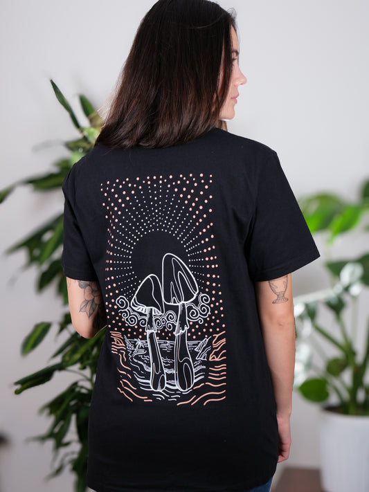Female model displaying the back of the Transcendent Love Tee, highlighting the intricate psychedelic mushroom and pacific coast beach artwork.